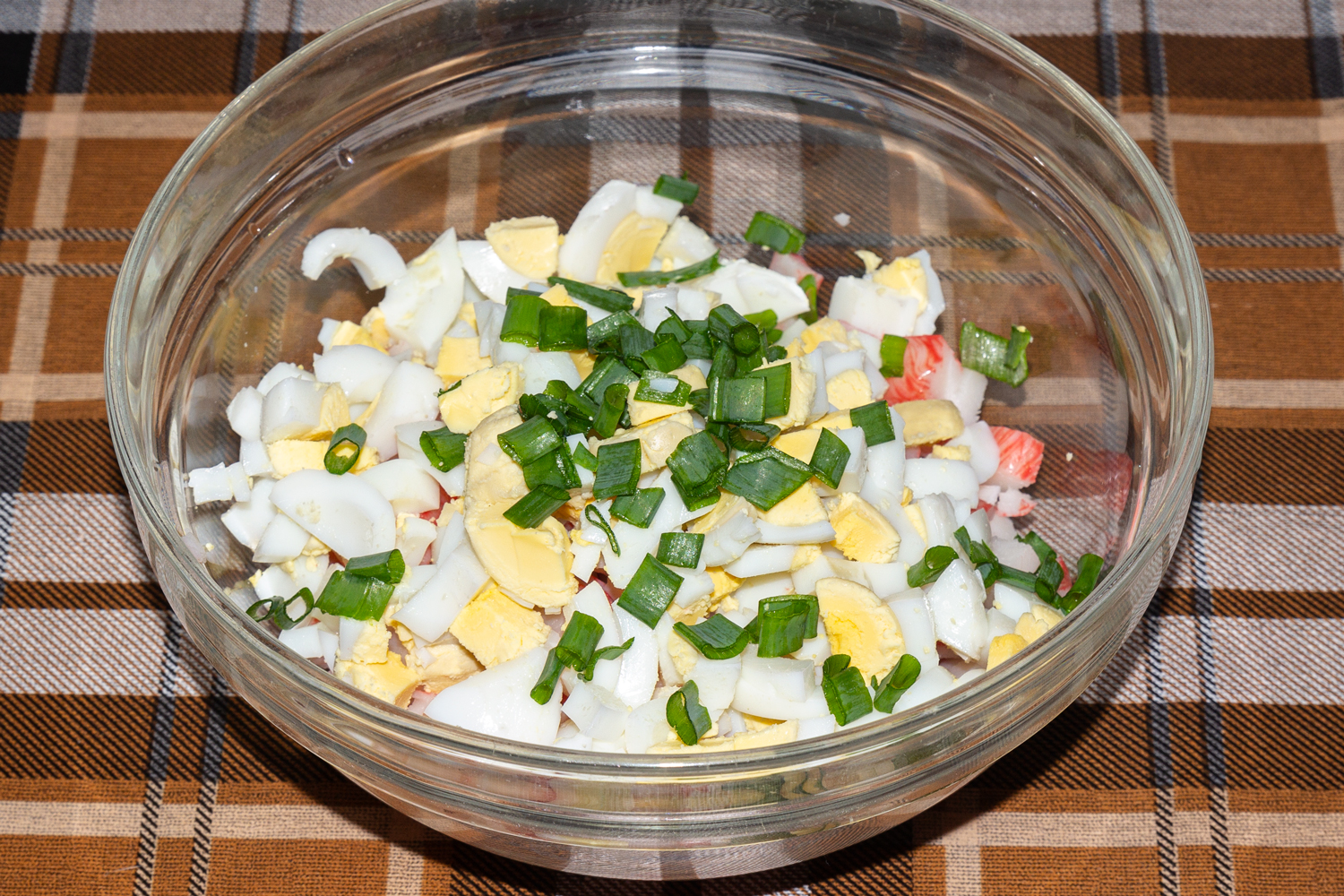 нарезанные яйца и зелень по рецепту Салат с крабовыми палочками, помидором, брынзой и яйцами