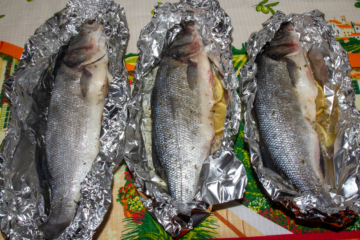 смажьте рыбу маслом и соком по рецепту Сибас в духовке с розмарином и лимоном