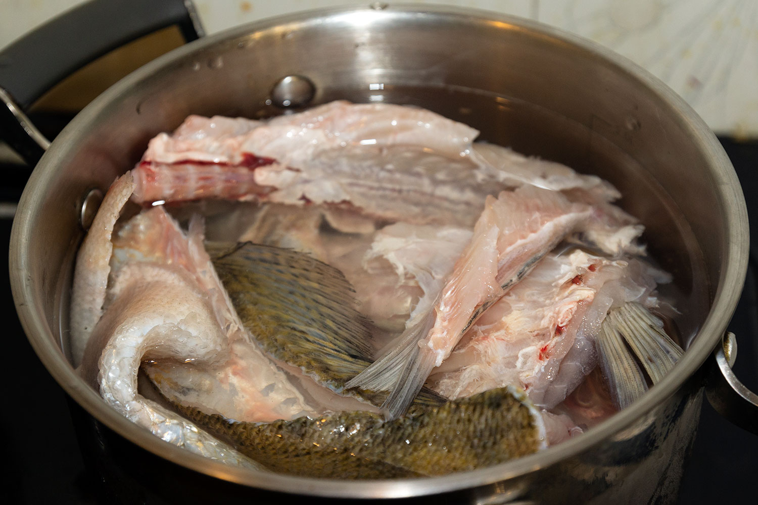 Выкладываем в кастрюлю головы, плавники и хребты для филе судака по-венгерски Выкладываем в кастрюлю головы, плавники и хребты